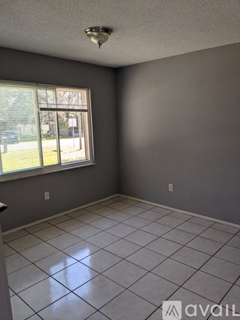 A room with a large window and tile flooring.