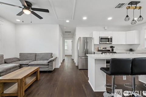 A modern kitchen with white cabinets and a black bar stool.