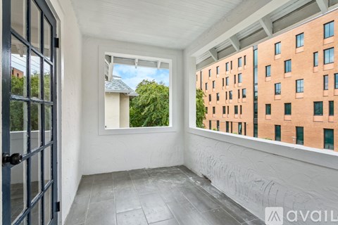 A balcony with a view of a green tree and a building with windows.
