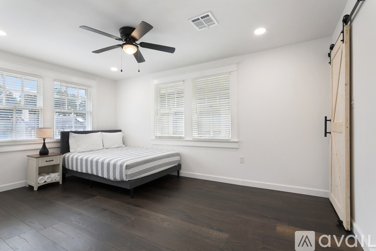 A bedroom with a bed, nightstand, and window with blinds.