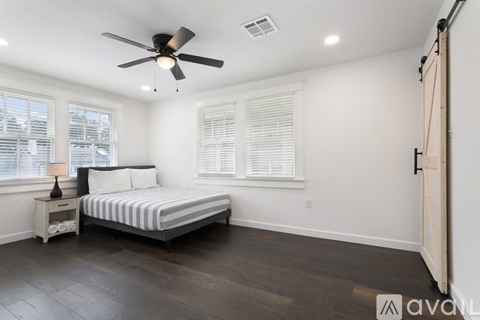 A bedroom with a bed, nightstand, and window with blinds.