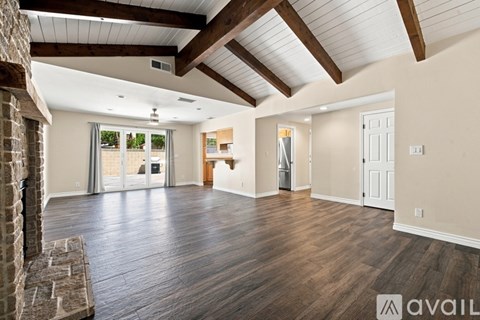 A spacious room with wooden floors and a stone fireplace.