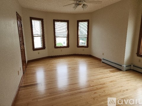 A room with wooden floors and three windows.