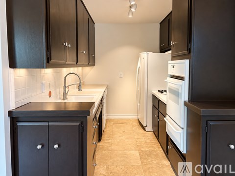 A kitchen with black cabinets and white appliances.