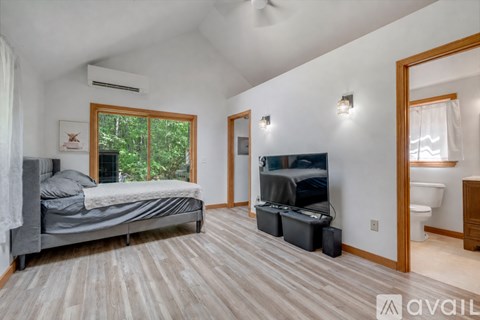 A bedroom with a bed, a television, and a window with a view of trees.