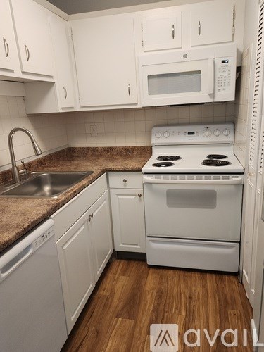 A kitchen with white cabinets and a white stove top oven.