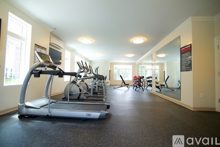 A gym with a treadmill, exercise bikes, and mirrors.