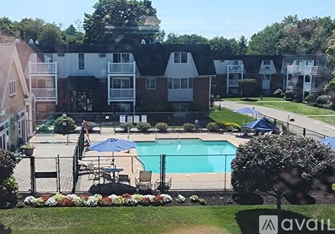 A pool surrounded by a fence and chairs with apartment buildings in the background.