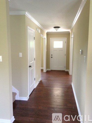 A hallway with wood floors and white walls.