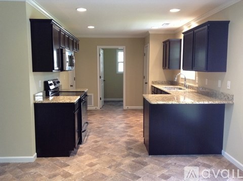 A kitchen with black cabinets and granite countertops.