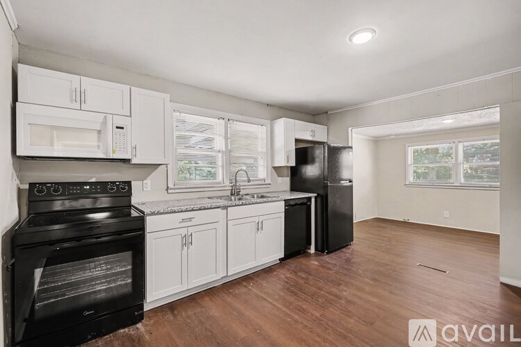 A kitchen with black appliances and white cabinets.