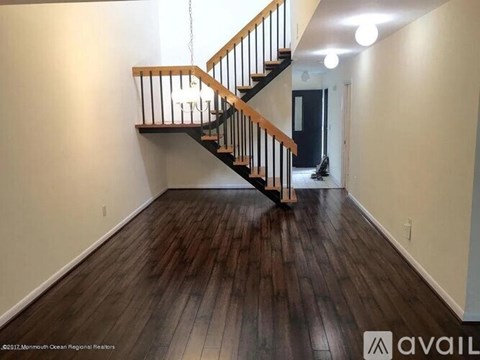 A spacious room with a wooden staircase and hardwood floors.