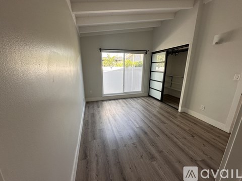 A room with wooden flooring and a sliding glass door leading to a balcony.