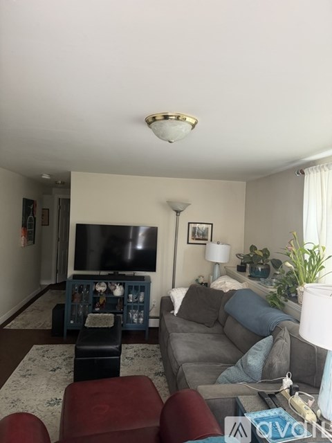 A living room with a grey couch and a television on a stand.
