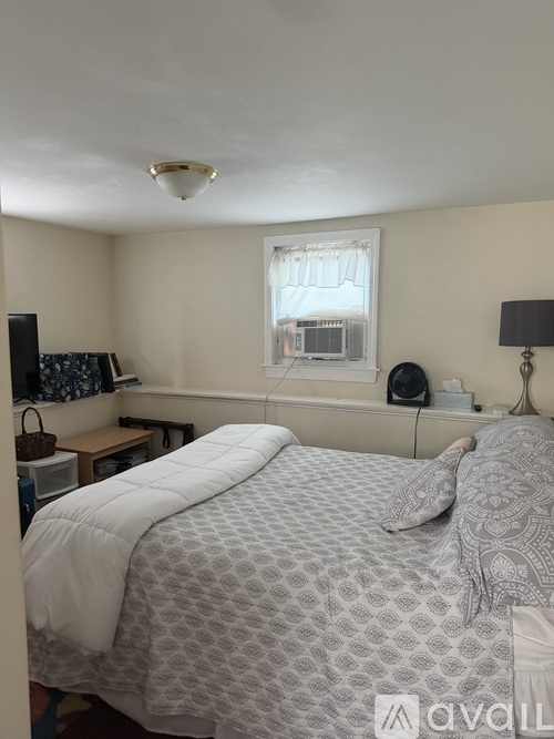 A bedroom with a bed, nightstand, and window.