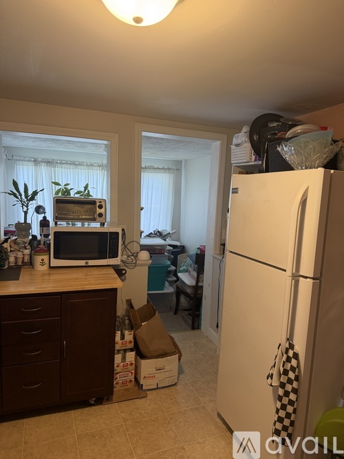 A kitchen with a white refrigerator and a counter with a microwave and other items.