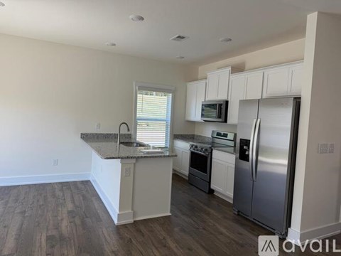 A kitchen with white cabinets and a granite countertop.