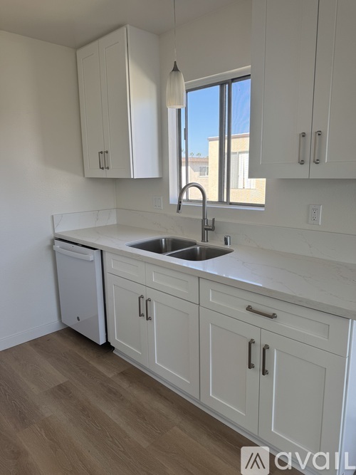 A kitchen with white cabinets and a wooden floor.