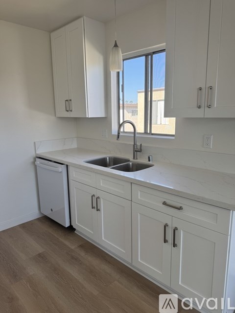 A kitchen with white cabinets and a wooden floor.