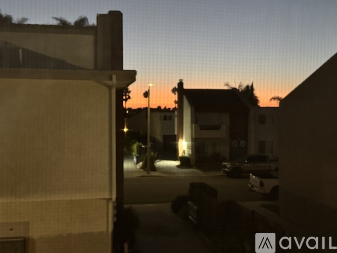 A view of a street at dusk with a building on the left and a car on the right.