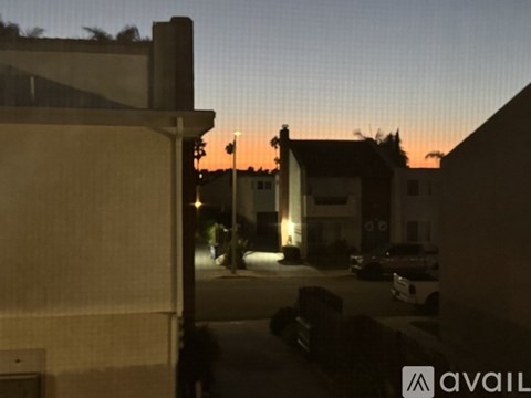 A view of a street at dusk with a building on the left and a car on the right.