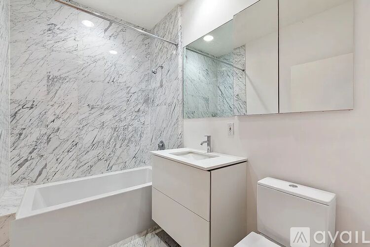 A bathroom with a marble wall and a white vanity.
