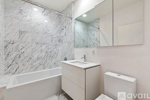 A bathroom with a marble wall and a white vanity.