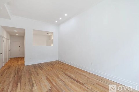 A room with wooden flooring and white walls.