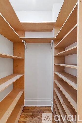 A walk-in closet with wooden shelves and a white door.