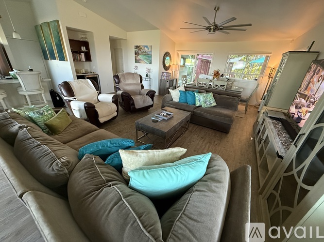 A living room with a brown couch and a blue pillow.