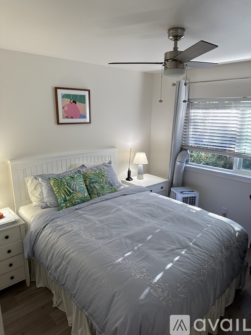 A bedroom with a bed, nightstand, and a ceiling fan.
