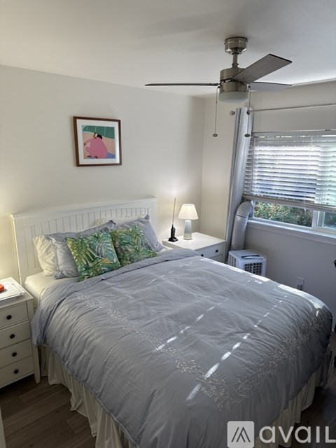 A bedroom with a bed, nightstand, and a ceiling fan.