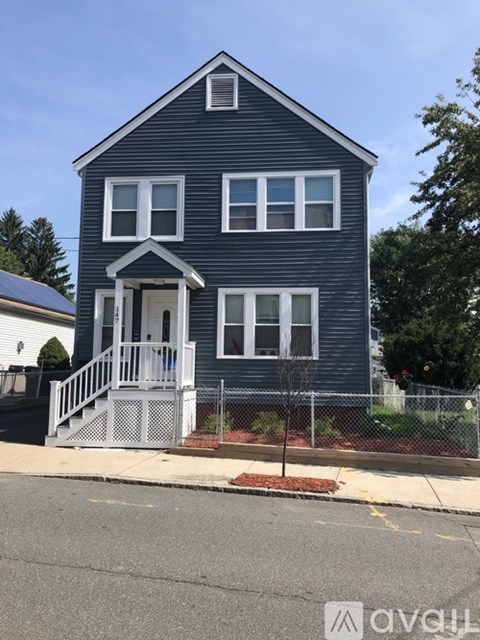 A two-story house with a front porch and a fence.