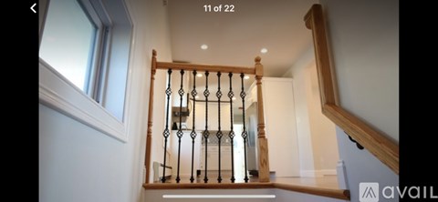 A staircase with a wooden banister and a light on the wall.