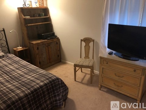 A bedroom with a bed, chair, and cabinet.