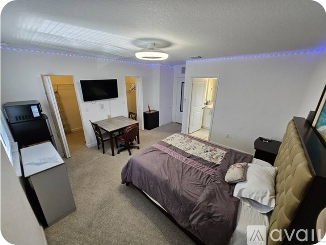 A bedroom with a bed, desk, and television.