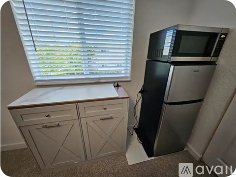 A kitchen with a white countertop, a window with blinds, and a microwave and oven built into the cabinetry.