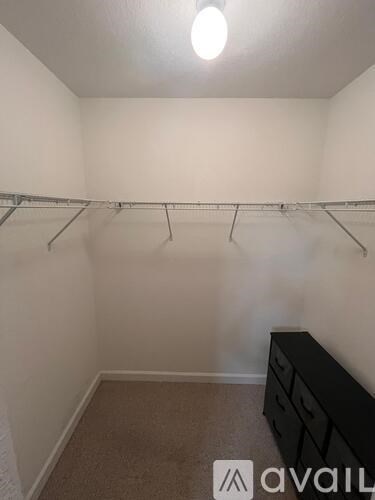 A small closet with a carpeted floor and a black dresser.