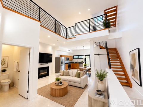 A spacious living room with a staircase and a fireplace.