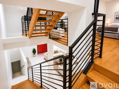 A black metal staircase with a wooden handrail and a red cabinet on the wall.