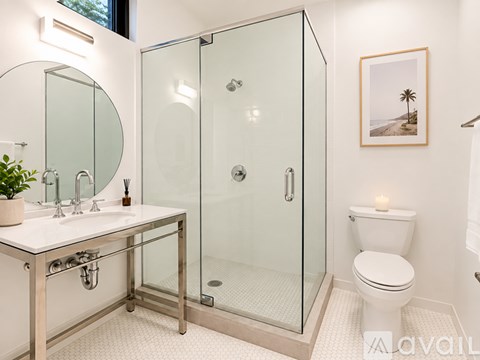 A bathroom with a glass shower stall and a toilet.