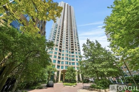A tall building with many windows is surrounded by trees.