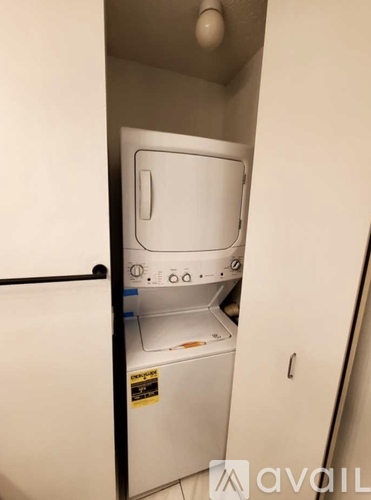 A small white washing machine in a narrow space.