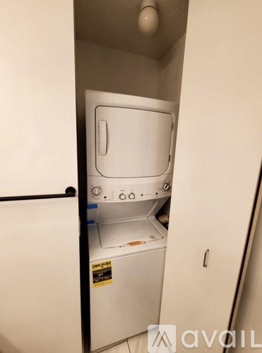 A small white washing machine in a narrow space.