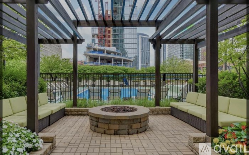 A patio with a fire pit and seating area overlooking a pool and buildings.