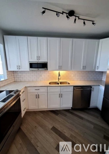 A kitchen with white cabinets and a wooden floor.