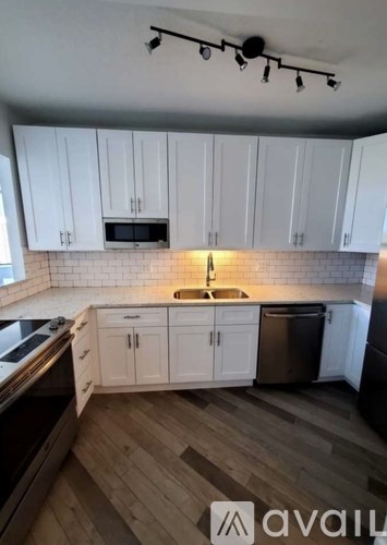 A kitchen with white cabinets and a wooden floor.