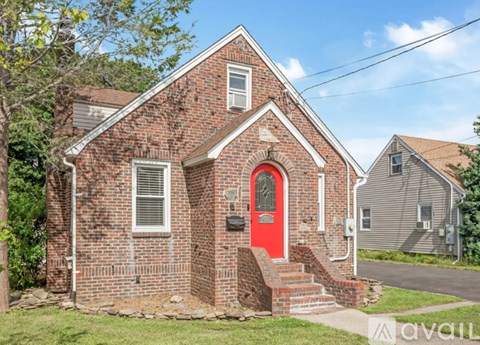 A red door is on the front of a brick house.