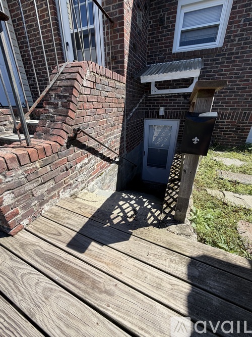 A mailbox is on a wooden deck in front of a brick building.