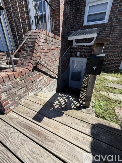 A mailbox is on a wooden deck in front of a brick building.